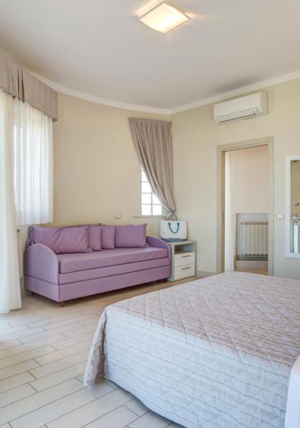 Camera luminosa con letto, divano viola e scrivania.