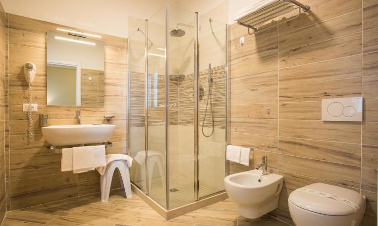 Salle de bain moderne avec douche en verre et carrelage effet bois.