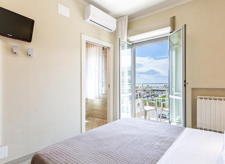 Helles Zimmer mit Doppelbett, Kleiderschrank und Nachttischen.