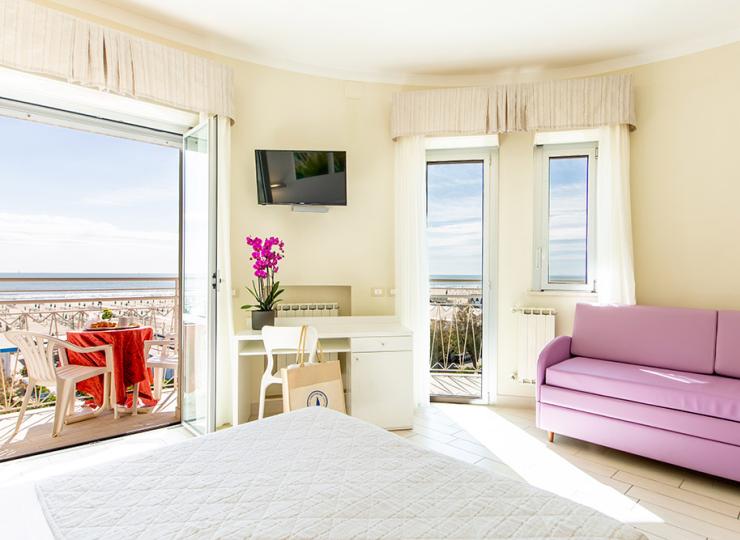 Modernes Zimmer mit Bett, Sofa und Schreibtisch.